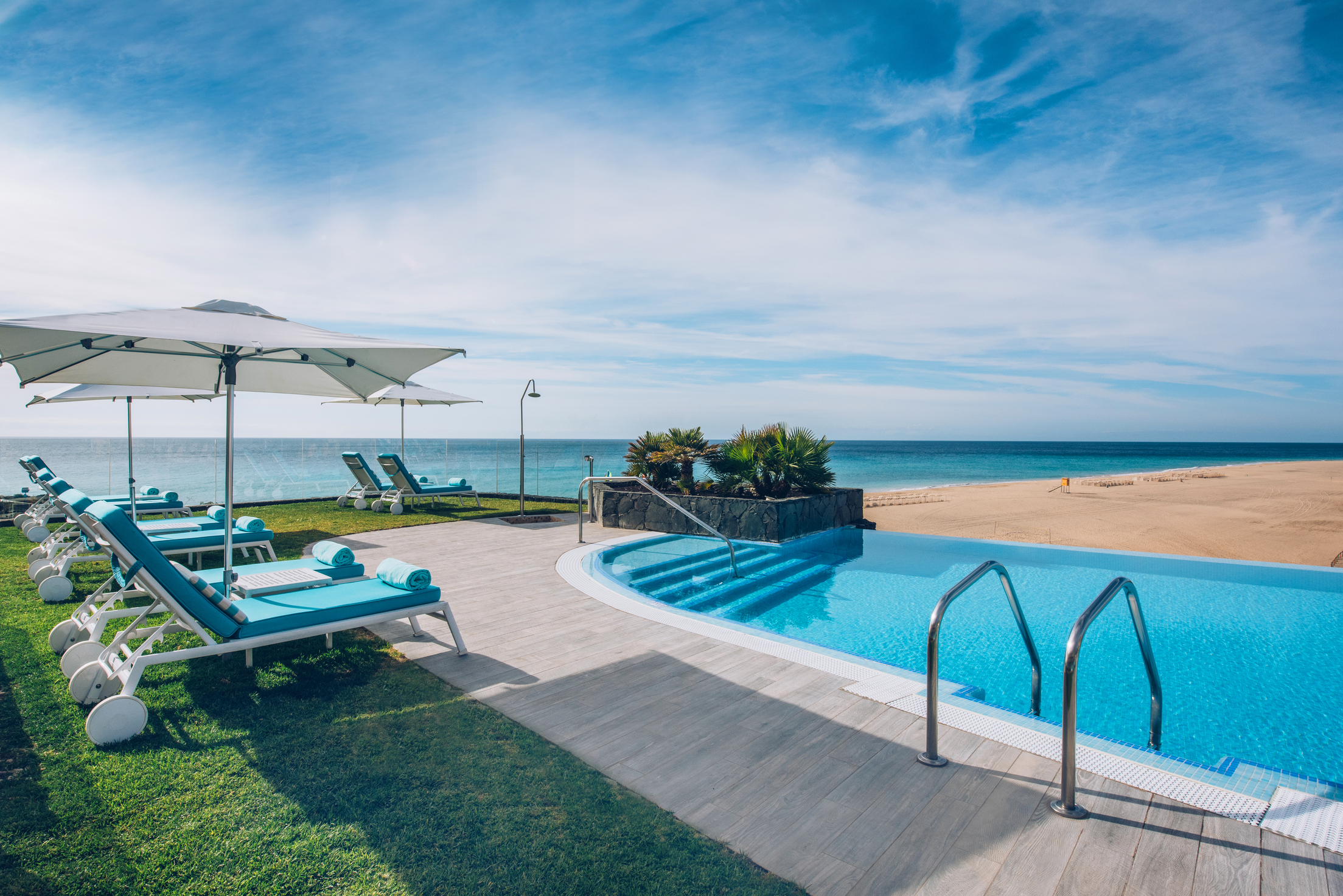Luxury beachfront pool with lounge chairs and umbrellas